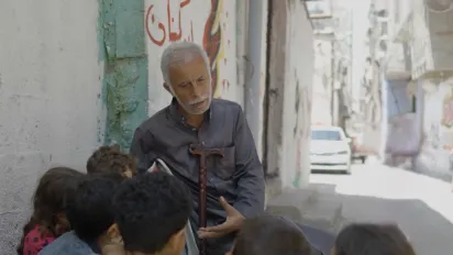 Older man speaking to children in the street 