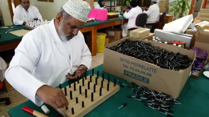 a man packaging plant for Amouage perfume bottles