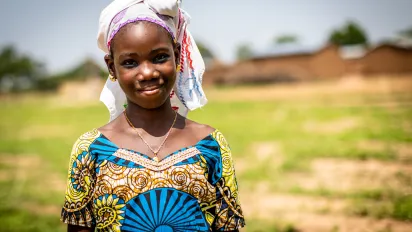 Young girl smiling, outside her village in Mali