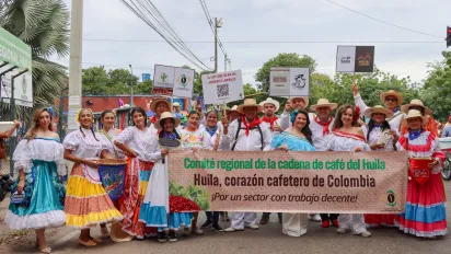 Integrantes del Comité Regional de la Cadena de Café, productores cafeteros y representantes de OIT, posan en el desfile folclorico departamental en la ciudad de Neiva, Huila, usando trajes típicos con el cartel “Comité Regional de la Cadena de café del Huila. Huila, corazón cafetero de Colombia. ¡Por un sector con trabajo decente!”