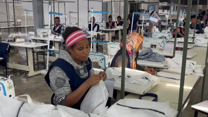 A women doing her trimming job in a garment factory.