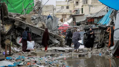 People crossing the road in front of a commercial shop destroyed during the war