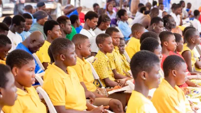 Children listen attentively in yellow uniforms