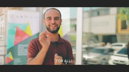A young man has his hand up, smiling