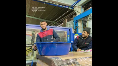 Two men smile as they work at a construction site