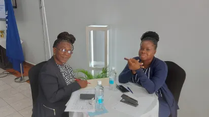 Two women at a table speaking about child labour