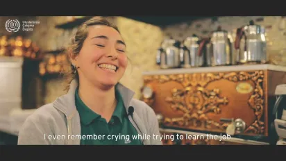 A young woman smiling against a tea boiler set in the background, in Turkiye