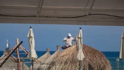 A man repairs a parasol in extreme heat in the Yucatán peninsula, Mexico