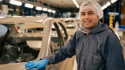 Trabajador de la industria automotriz mientras pule el chasis de un auto