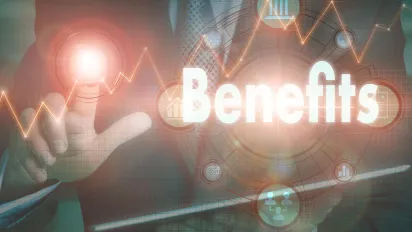A businessman operating a computer display with a Benefits business word concept on it