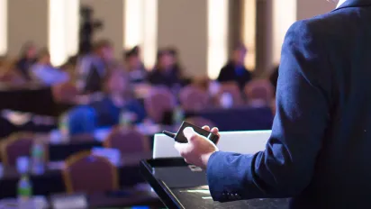 A businessman giving a speech to a defocused blurred audience in a conference hall
