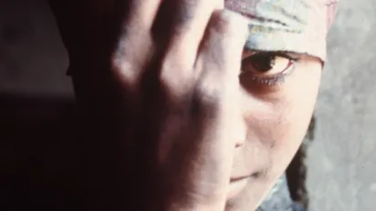 Portrait of young woman hiding behind her hand and scarf