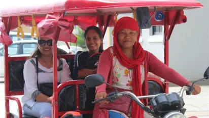 A woman driving an electronic rickshaw, striving for economic independence.