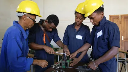 3 people wearing yellow helmets are learning new skills in mechanics