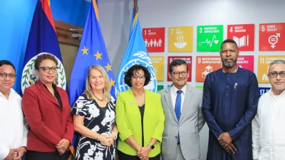 A group of people standing in front of flags and SDG banner