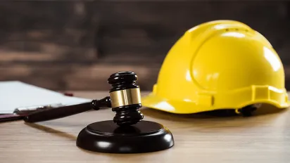 A brown gavel and a yellow safety helmet