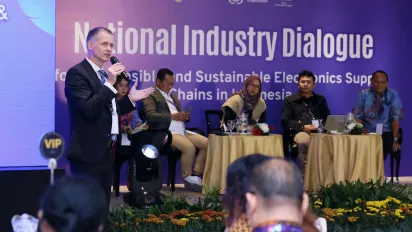 Four people sitting on the stages with one of the speaker standing doing a presentation.