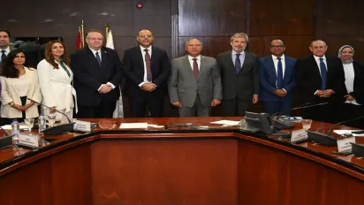 Group of diverse professionals in formal attire at a conference table during a business meeting, highlighting a collaborative corporate environment.