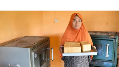 a woman in orange hijab baking some breads