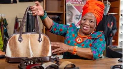  A woman siting at a table and presenting a leather bag