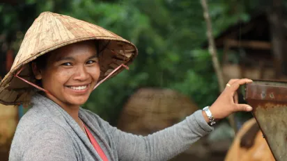 A woman, wearing a straw hat, smiled.