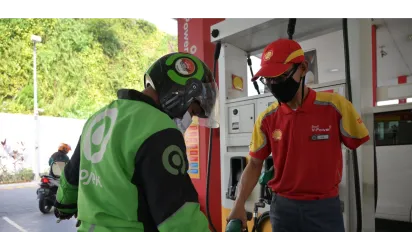 a male disabled worker in a gas station refilling fuel into a motorcycle