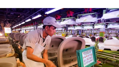 a male worker cleans the washbasin production area inside the factory