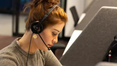 Young woman sitting in front of a computer with a headset
