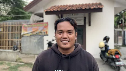A man stands in front of a newly built house. 