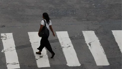 Mulher atravessa faixa de pedestres em uma rua não identificada no Rio de Janeiro