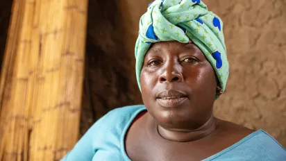 Portrait of a woman wearing a green and blue head wrap, looking directly at the camera.