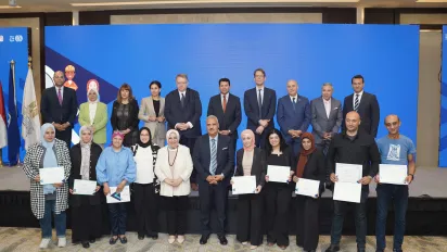 A formal group photo showing facilitators of the Job Search Club training programme holding certificates of recognition. They are joined by officials from the ILO, the Ministry of Youth and Sports, and development partners, standing in front of a blue backdrop at the award ceremony.