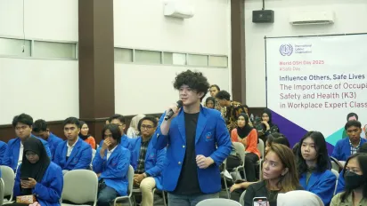 A group of students joining a seminar with one student standing up holding a mic