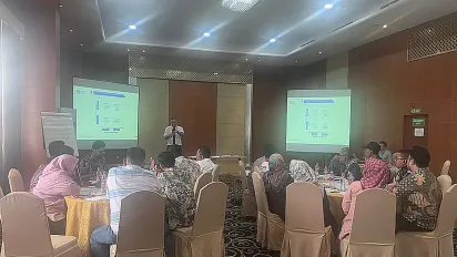 A meeting with participants sitting and one person standing on the front