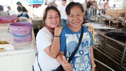 two women smiling at the camera at a covered fish market