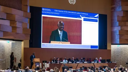 Large video screen feature the ILO Director Genral addressing the assembly