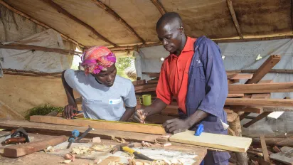 man trainer teaching a woman student wood working skills