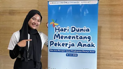 A teen girl standing in front of the banner