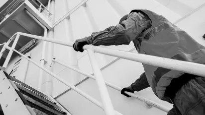 A seafarer climbing onto the deck of a ship