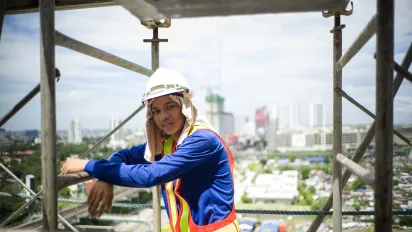 a young male construction worker wearing a hard hat on top of a building