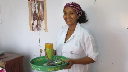 BRMM beneficiary holding juice and smiling at the camera