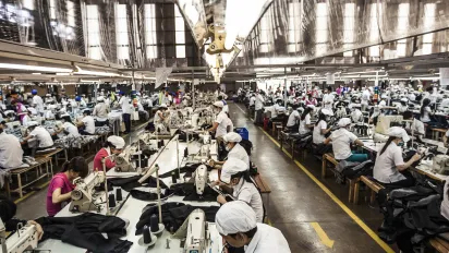 Wide shot of the garment factory featuring row of busy workers 