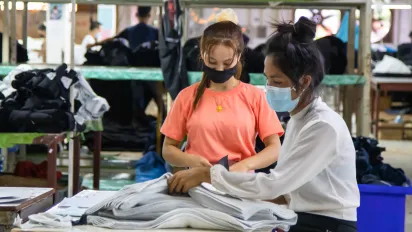 Two female garment workers folding fabrics. 