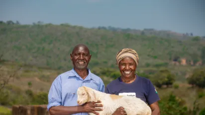 A man and a woman holding a lamb together and smiling at the camera  