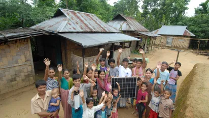 Villagers gather around a solar panel.