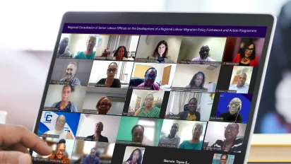 A close-up of a laptop screen showing a virtual meeting with multiple participants arranged in a grid format. The banner at the top reads: “Regional Consultation of Senior Labour Officials on the Development of a Regional Labour Migration Policy Framework and Action Programme.”