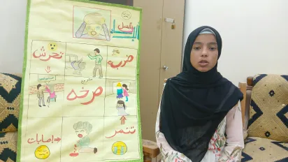 Mahasen, a 15-year-old girl from Egypt stands next to a poster of her making.
