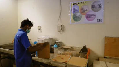 a male worker arranging his work corner with 5S poster on the wall