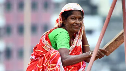 Female construction worker crouching down, holding a tool in her hand