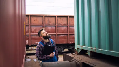 Railroad worker supervisor inspecting shipping cargo container at freight train station